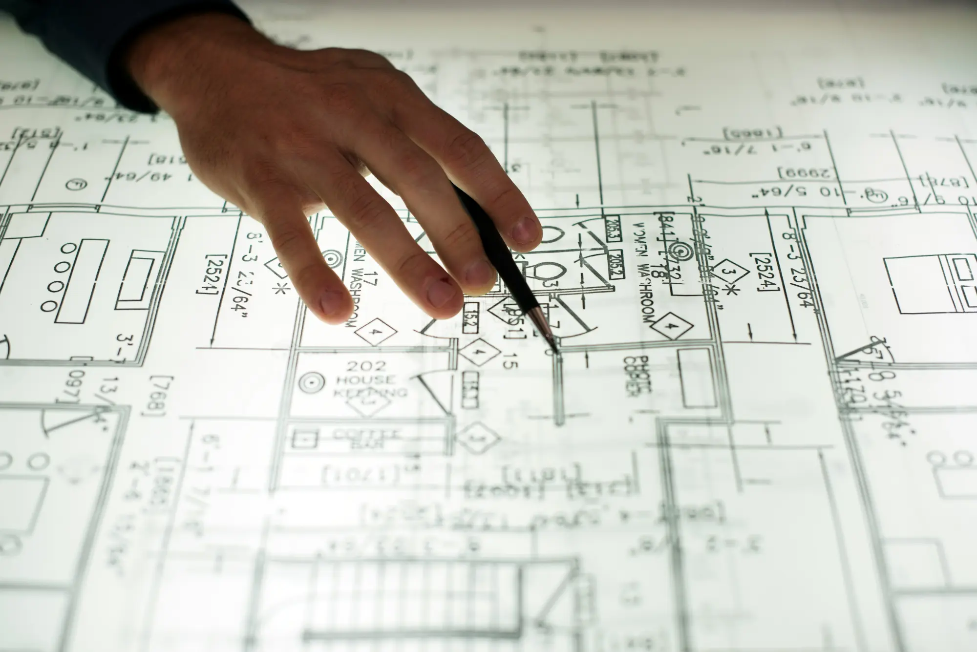 Exhibition Booth in Laval or Longueuil: Complete Guide 2 Hand pointing with a pencil at a detailed layout plan with measurements and annotated rooms
