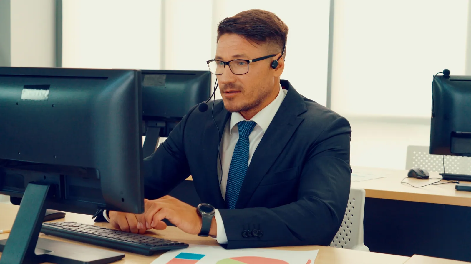 Representative wearing a headset making follow-up calls to leads in front of two work screens