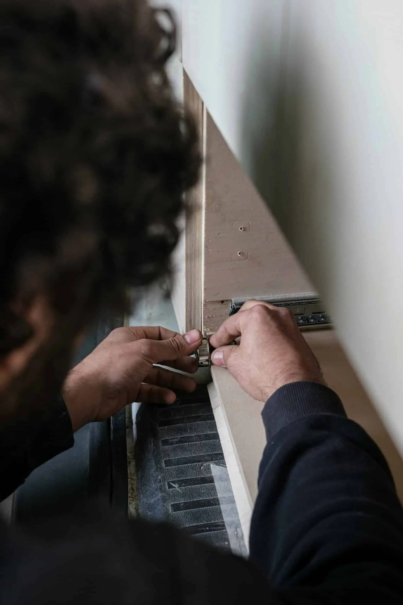 Mains d'un technicien fixant un connecteur métallique sur un panneau lors du montage d'un stand modulaire