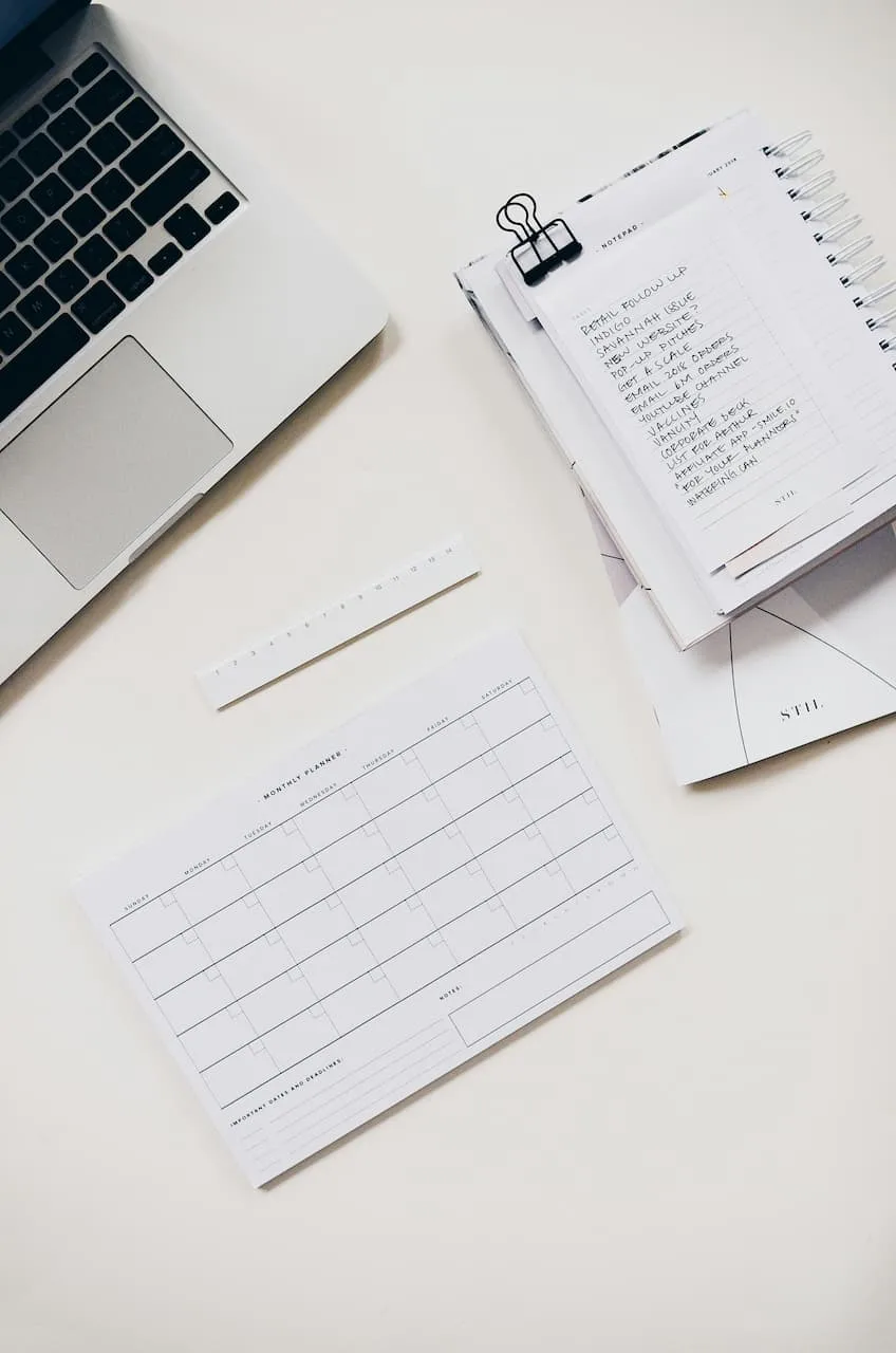 Bureau avec un ordinateur portable, un calendrier mensuel vierge et une liste de tâches manuscrite