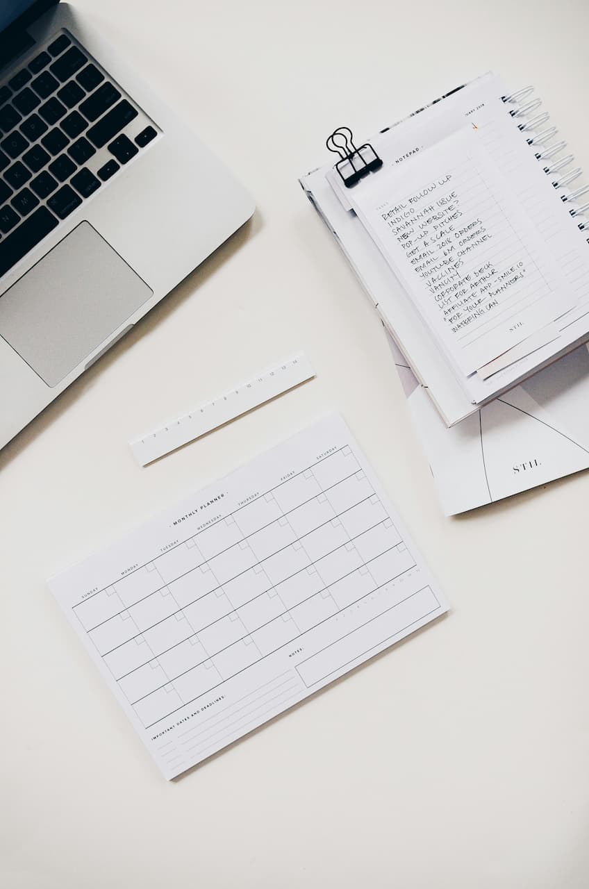 Bureau avec un ordinateur portable, un calendrier mensuel vierge et une liste de tâches manuscrite