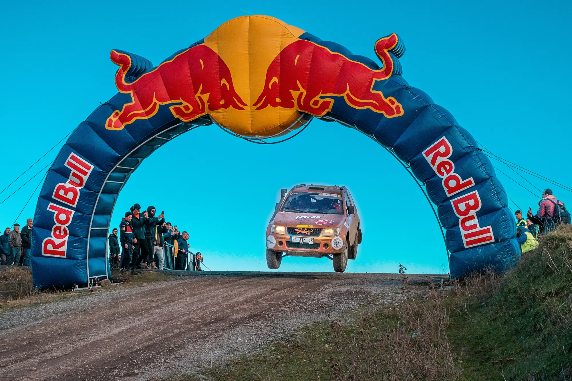 Arche gonflable publicitaire au-dessus d'un parcours de rallye, avec une voiture en plein saut