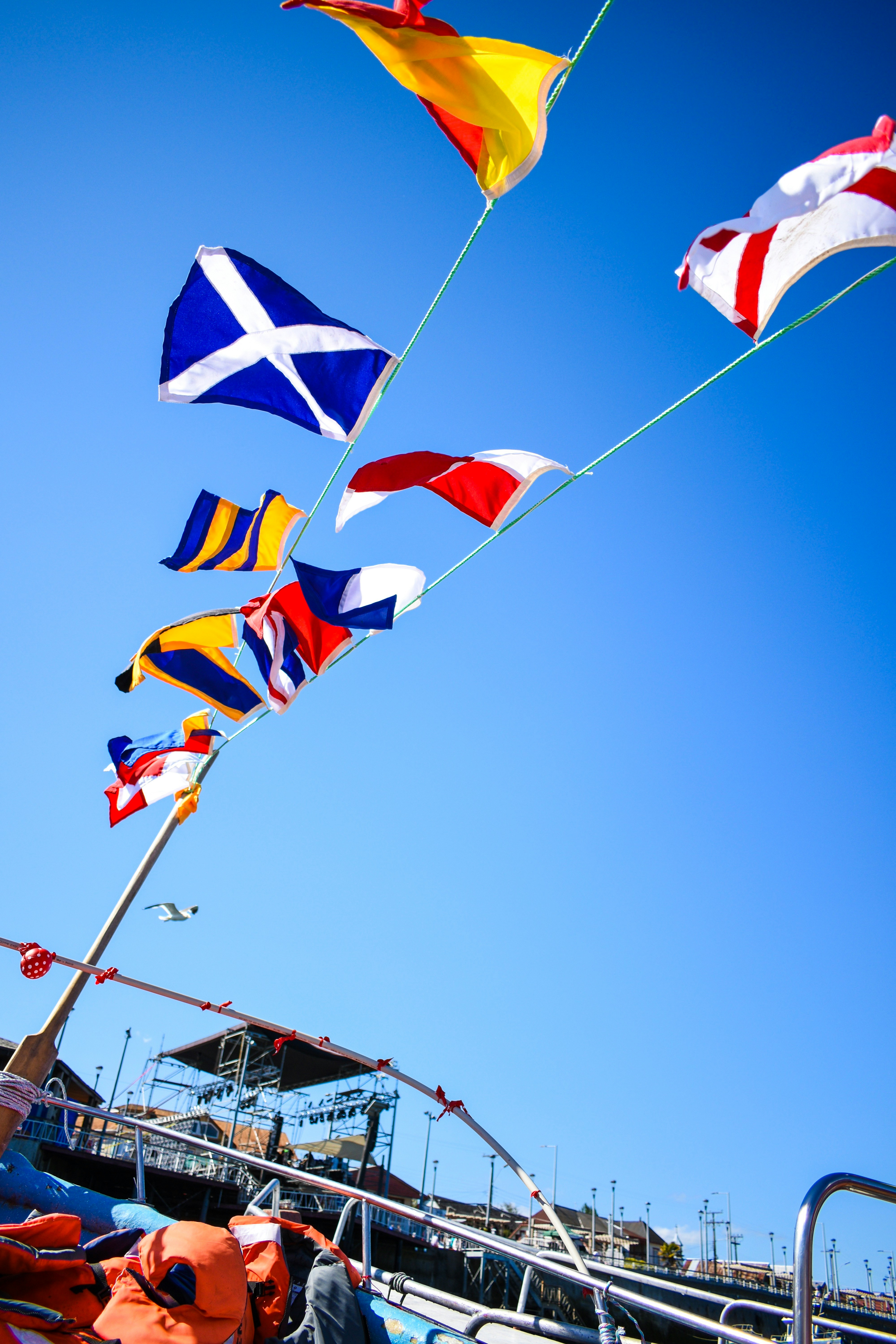 Drapeaux colorés flottant au vent contre un ciel bleu au-dessus d'un quai