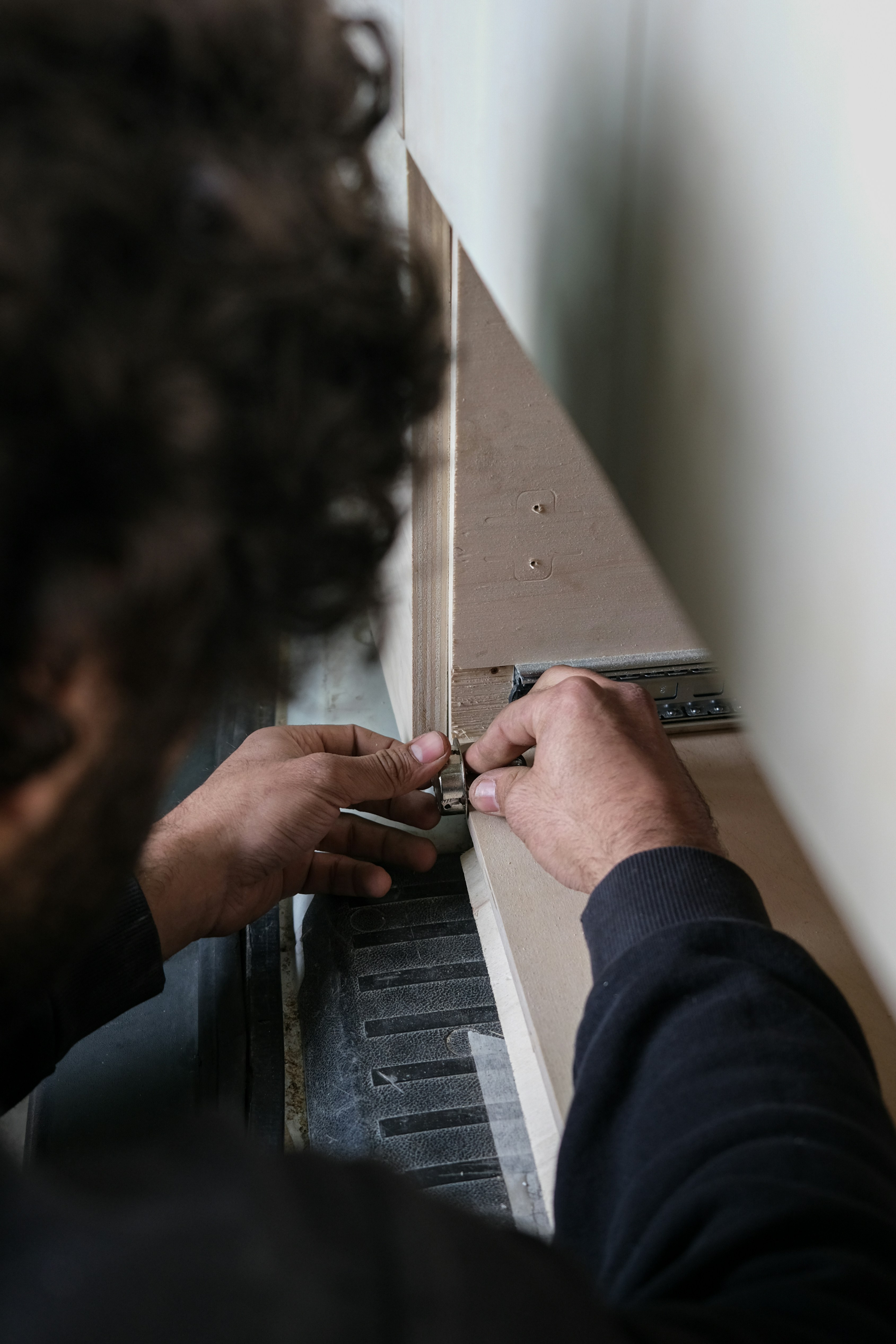 Mains d'un technicien fixant un connecteur métallique sur un panneau lors du montage d'un stand modulaire