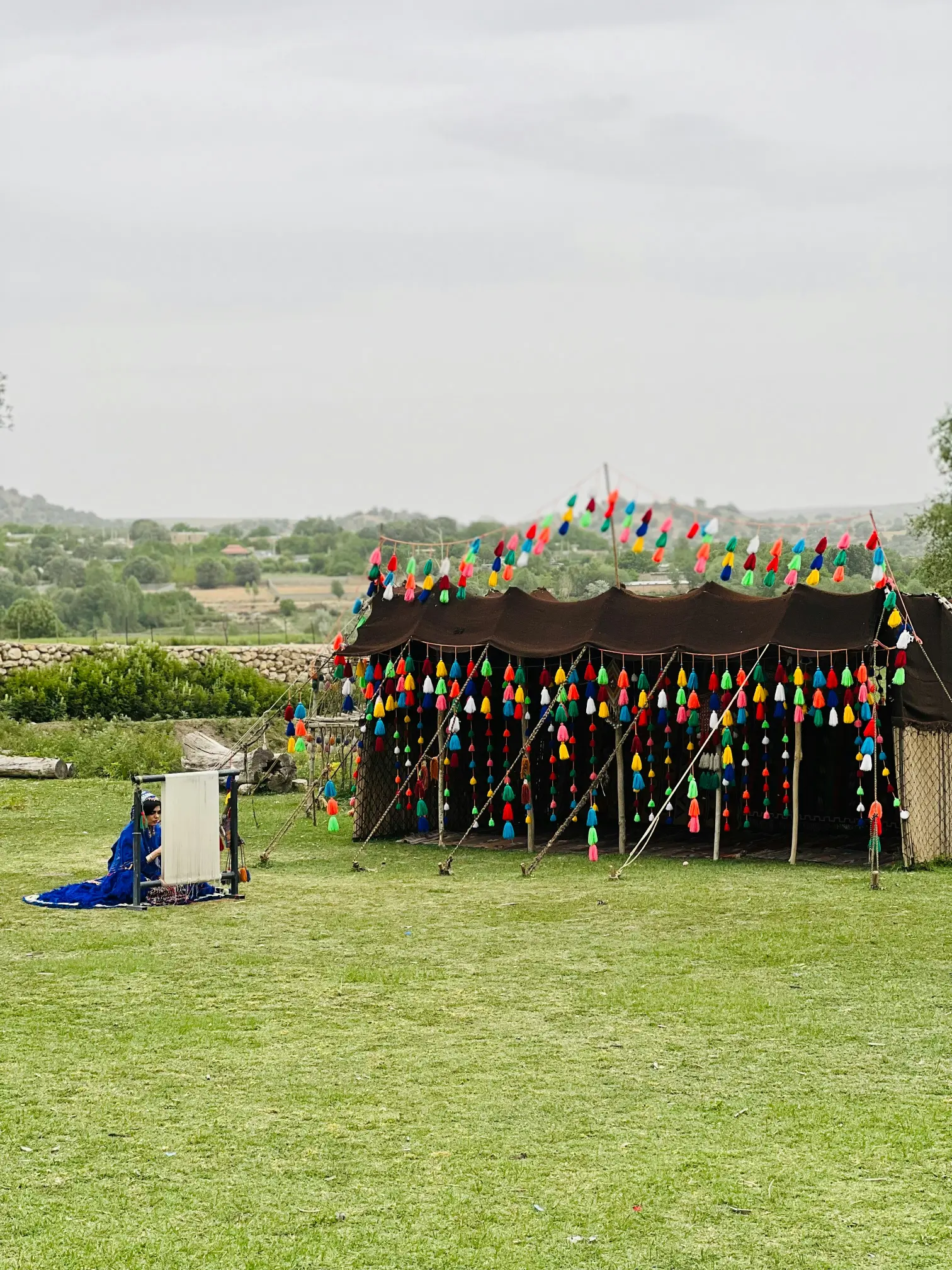 Tente traditionnelle décorée de pompons colorés installée sur une pelouse en plein air